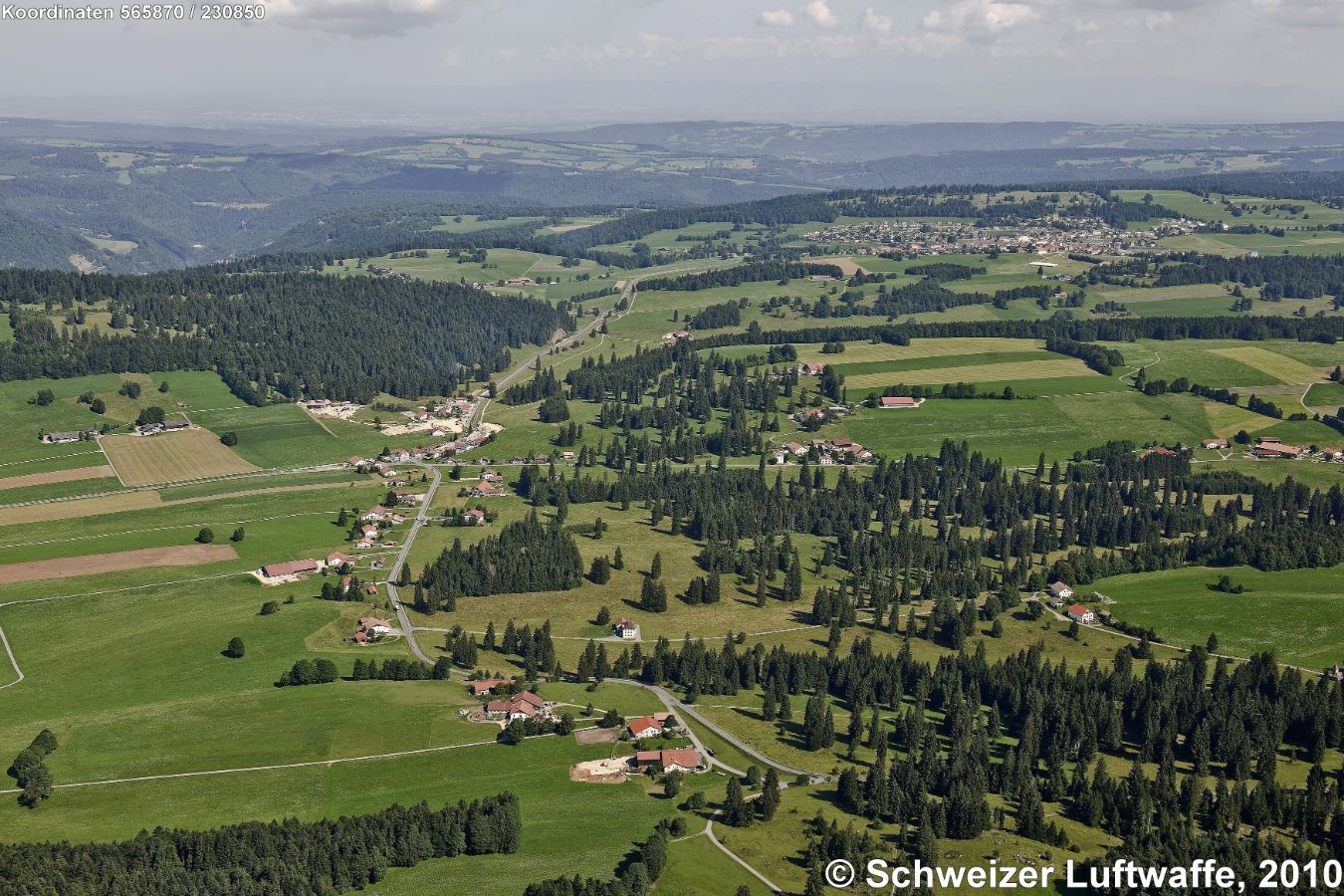 Les Emibois (Position 2'565'553.52, 1'231'334.32). Grosse Siedlung hinten rechts: Saignelégier. Weiler im Vordergrund: Les Peux.